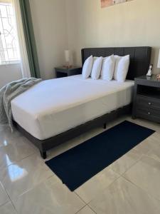 un grande letto con lenzuola e cuscini bianchi in una camera da letto di Paris' -Oasis a Discovery Bay