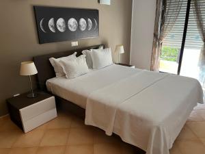 a bedroom with a large bed with white sheets and pillows at Margarida Apartment in Luz +14 photos