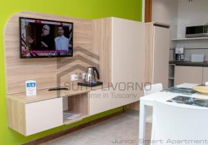 a kitchen with a tv on a wall at Suites Marilia Apartments - Suite Livorno Holiday Home Group in Livorno