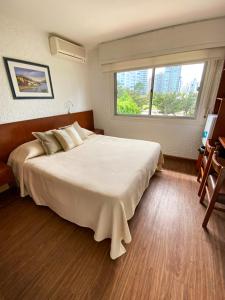 a bedroom with a large white bed and a window at Hotel Ajax in Punta del Este