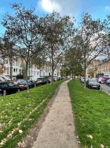 a path in a park with trees and parked cars at Top Floor Apartment in Islington in London