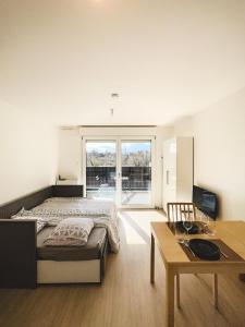 a bedroom with a bed and a desk and a table at Studio Le Hésingue- Near Airport, Swiss & German board in Saint-Louis