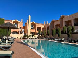 a swimming pool with chairs and umbrellas in a resort at Margarida Apartment in Luz