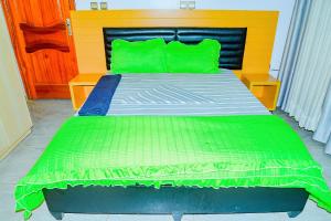 um quarto com uma cama com almofadas verdes em Venus VIP VILLA SUITES em Kigali