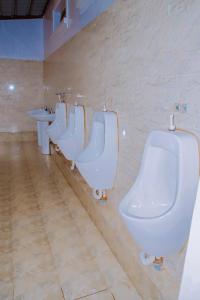 une rangée d'urinoirs blancs dans une salle de bains dans l'établissement AIRPORT COMFORT APARTMENT MILITARY HOSPITAL, à Kigali
