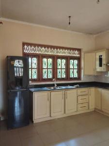 Holiday Home in Mirigama في Mirigama: مطبخ فيه دواليب بيضاء وثلاجة سوداء