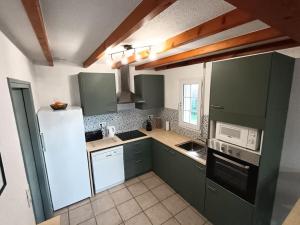 eine Küche mit grünen Schränken und einem weißen Kühlschrank in der Unterkunft Maison 4 ch*L'Aiguillon s/ Mer in LʼAiguillon-sur-Mer