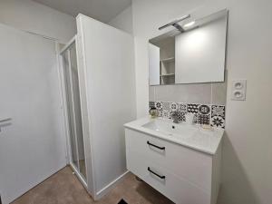 ein weißes Badezimmer mit einem Waschbecken und einem Spiegel in der Unterkunft Maison 4 ch*L'Aiguillon s/ Mer in LʼAiguillon-sur-Mer