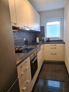 a kitchen with white cabinets and a window at WellandHome- Deluxe Apartment Schechingen in Schechingen