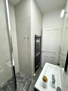 a white bathroom with a shower and a sink at L Étoilé Appartement tout confort à Epinal Gare Classé 3 étoiles in Épinal