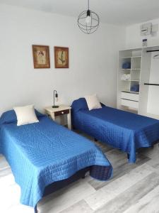 a bedroom with two blue beds and a desk at Duplex Victoria in Luján