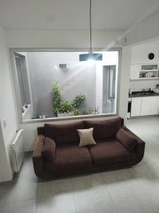 a brown couch in a living room with a large window at Duplex Victoria in Luján