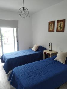two beds in a room with blue sheets at Duplex Victoria in Luján