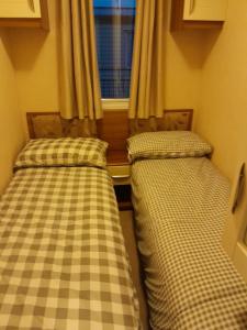 two beds in a small room with a window at Sunnymeade Holiday Park i3 St David in Ingoldmells