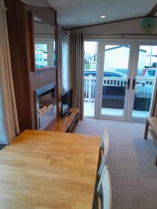 ein Wohnzimmer mit einem Tisch und Blick auf einen Balkon in der Unterkunft Sunnymeade Holiday Park i3 St David in Ingoldmells
