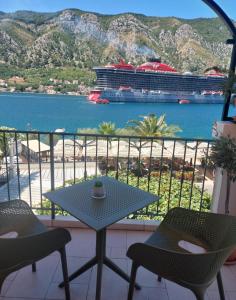 a table and chairs on a balcony with a cruise ship at Guesthouse Anita in Kotor