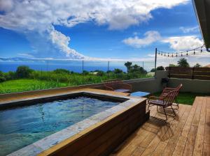 una piscina con 2 sillas en una terraza en L'ApparT, meublé de tourisme 4 étoiles, piscine chauffée et vue mer imprenable, en Les Avirons