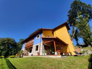 a large yellow house on a green lawn at La Biesca Sebreñu in Ribadesella