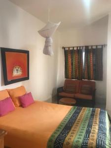 een slaapkamer met een bed en een stoel bij Résidence Keur Fleurie in Toubab Dialaw