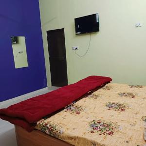 uma cama num quarto com um cobertor vermelho em Saraswati Sadan Homestay Ayodhya em Faizābād