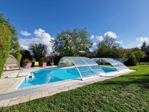 a swimming pool with a retractable canopy around it at Chez Patou - Chambres d'hôtes in Beauzac