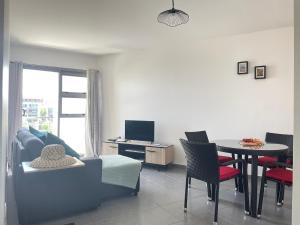 a living room with a couch and a table with chairs at Appartement avec vue sur le port de Papeete in Faaa