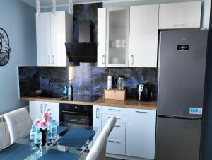 a kitchen with white cabinets and a table and a refrigerator at Apartament u Bączków in Gdynia
