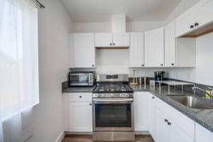 a kitchen with white cabinets and a stove and a sink at Entire First-Floor 3-Bedroom w Gated Yard, Laundry, Crib, Fast Wi-Fi, Private Rental, No Deposit in San Diego