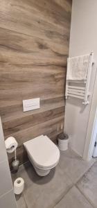 a bathroom with a white toilet and a wooden wall at Apartament Czarna Góra MOON in Sienna