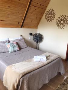 sypialnia z dużym łóżkiem i wentylatorem w obiekcie Chalés Flor do Caparaó em Patrimonio da Penha w mieście PatrimÃ´nio da Penha