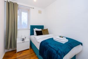 een slaapkamer met een bed met een blauwe deken bij Spacious 3BR, 5min Penge St, Crystal Palace Park in Sydenham
