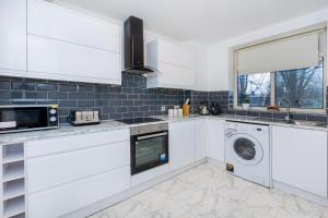 a kitchen with white cabinets and a washer and dryer at Spacious 3BR, 5min Penge St, Crystal Palace Park in Sydenham