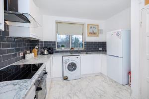 a white kitchen with a washer and dryer in it at Spacious 3BR, 5min Penge St, Crystal Palace Park in Sydenham