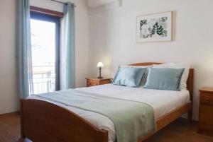 a bedroom with a bed with blue pillows and a window at Seashell Bay - Beach House - in São Martinho do Porto