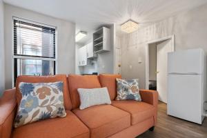 an orange couch in a living room with a refrigerator at Inspiring Urban Life, Times square Apartments in New York