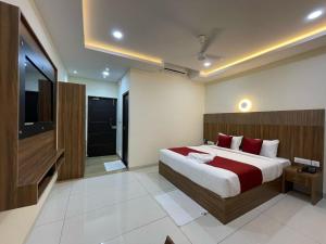 - une chambre avec un grand lit et une télévision dans l'établissement Deepakam Inn, à Palakkad