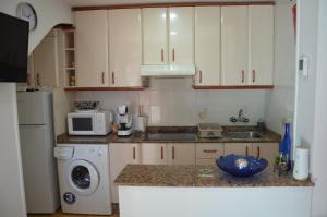 a kitchen with white cabinets and a washer and dryer at Casita Amalia in Santa Pola
