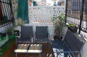 two chairs and a bench on a balcony with plants at Casita Amalia in Santa Pola