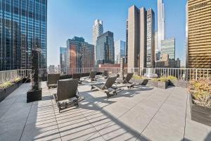 a row of lounge chairs on a rooftop in a city at PlanURstay - Spacious Midtown West Fully-Serviced - 1BR & 1BTH in New York