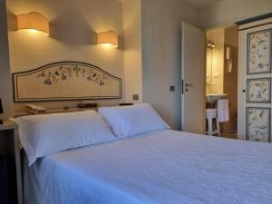 una camera da letto con un grande letto bianco con due cuscini di Hotel Virgilio a Orvieto