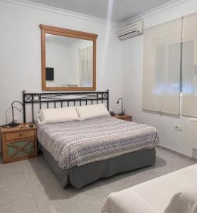 ロタにあるHostal Playa Hidalgoのベッドルーム1室(ベッド1台、壁掛け鏡付)