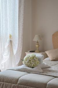 two beds with white curtains and a bouquet of roses at Giramondo Guest house in Fiumicino