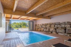 una piscina en una casa con una pared de piedra en Moderne corps de ferme - Piscine, en Grésy-sur-Aix