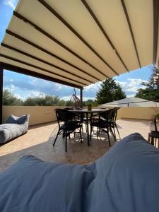 un patio con mesa y sillas bajo una sombrilla grande en Villa KIMA Heated Pool en episkopi-heraklion