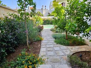 a stone path in a garden with flowers and trees at CASADÔ in San Pancrazio Salentino
