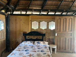 1 dormitorio con 1 cama en una habitación con paredes de madera en Punta Arena EcoHostal and EcoFit – Your Eco-Friendly Oasis 02 en Cartagena de Indias