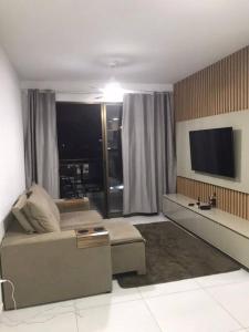 uma sala de estar com um sofá e uma televisão de ecrã plano em Apartamento em Praia Grande em Arraial do Cabo