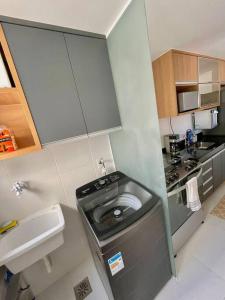 a small kitchen with a sink and a washing machine at Apartamento em Praia Grande in Arraial do Cabo
