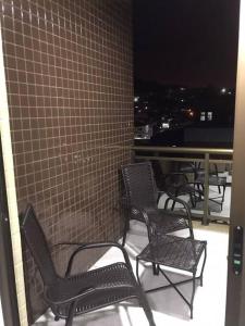 a group of chairs sitting on a balcony at night at Apartamento em Praia Grande in Arraial do Cabo