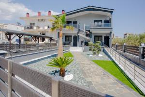 a view of a house with a fence and a palm tree at ONAR PALACE in Nea Peramos